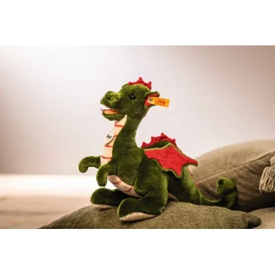 Peluche Rocky le dragon signée Steiff sur un coussin Peluche Rocky le dragon signée Steiff sur un coussin