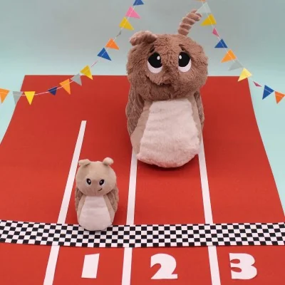 Peluche escargot Speedou maman et son bébé brun signée Les Deglingos, sur une piste de course Peluche escargot Speedou maman et son bébé brun signée Les Deglingos, sur une piste de course