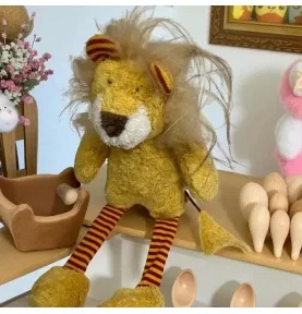Peluche lion bio signée Pat & Patty, assis sur une étagère